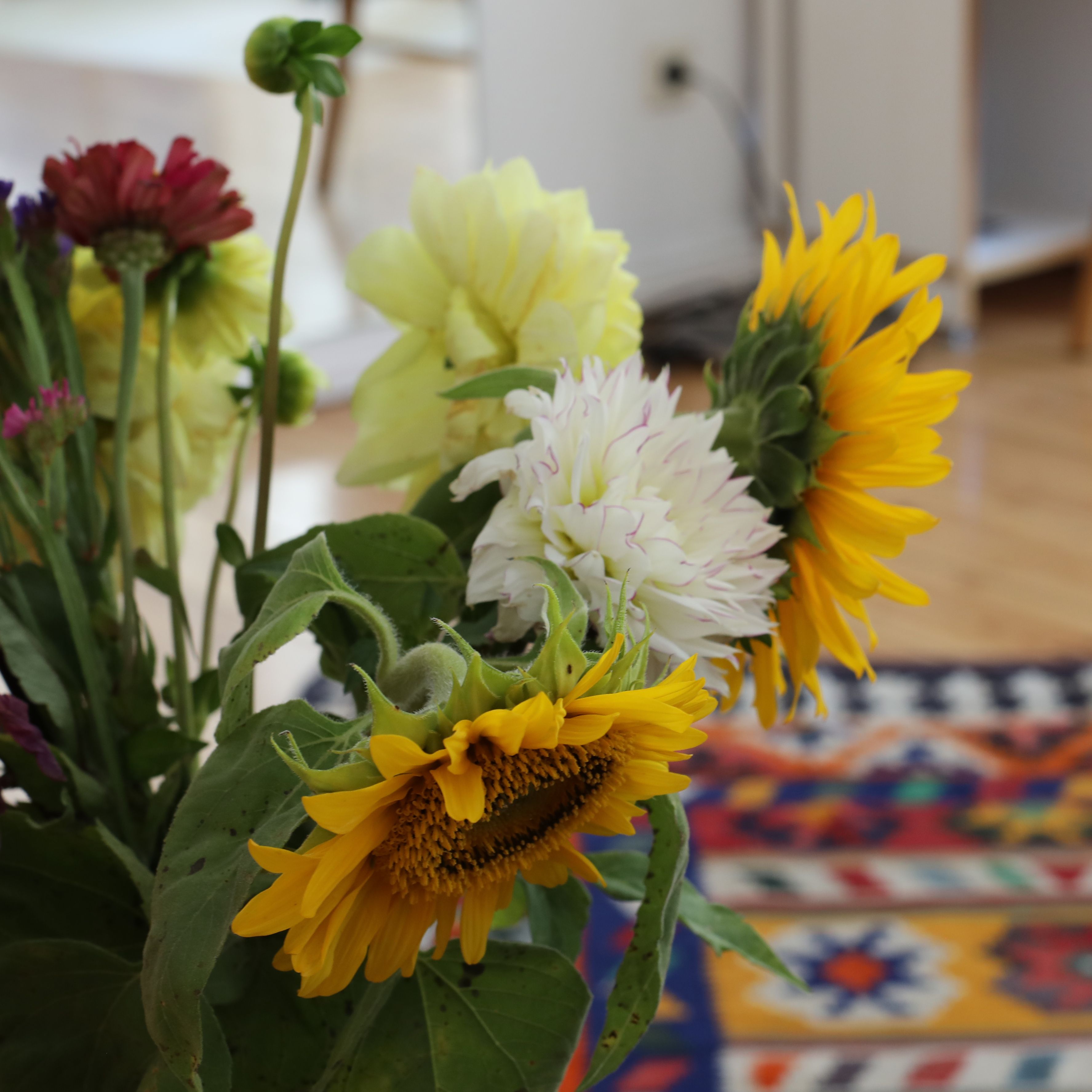 bunter Blumenstrauß mit Sonnenblumen und im Hintergund ein bunter Teppich